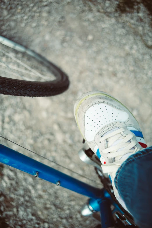 a persons foot and their sneakers on top of a bike tire