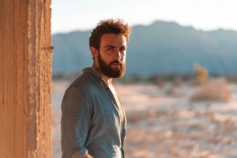 bearded man standing at edge of building in desert