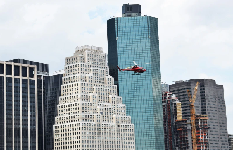 the helicopter is flying by tall buildings