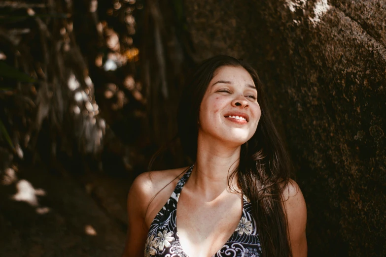 a pretty woman wearing a halter top in front of a rock