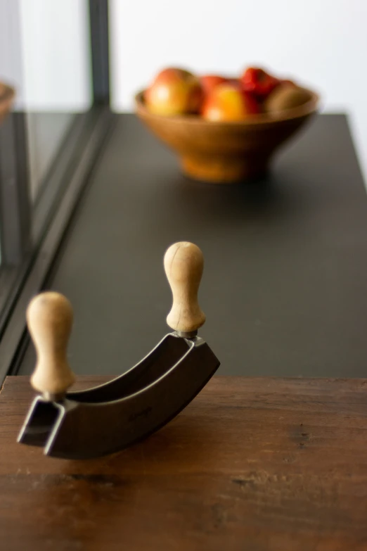 small wooden toy sitting on a table next to a bowl of fruit