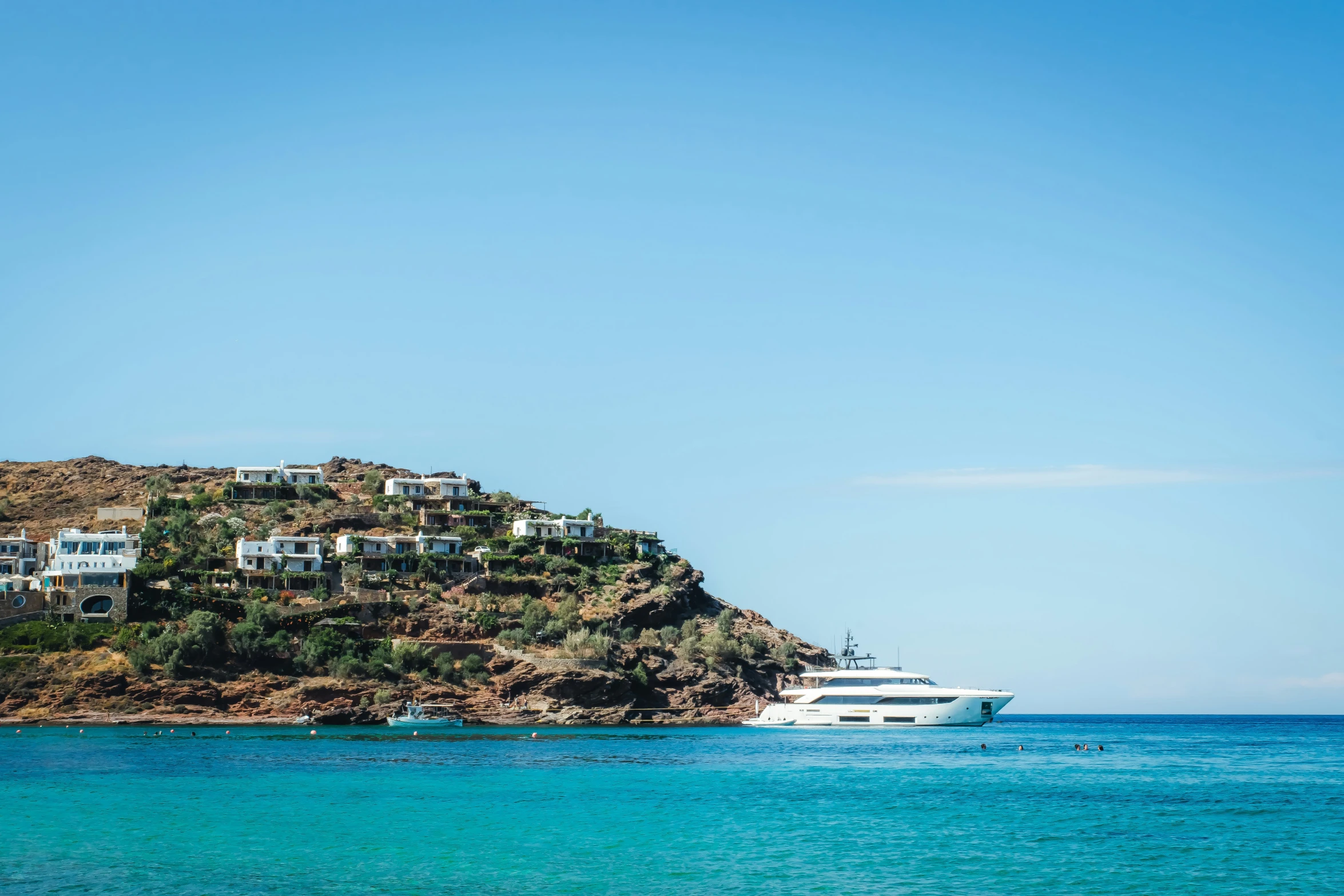 a white boat sits in the ocean near a small island