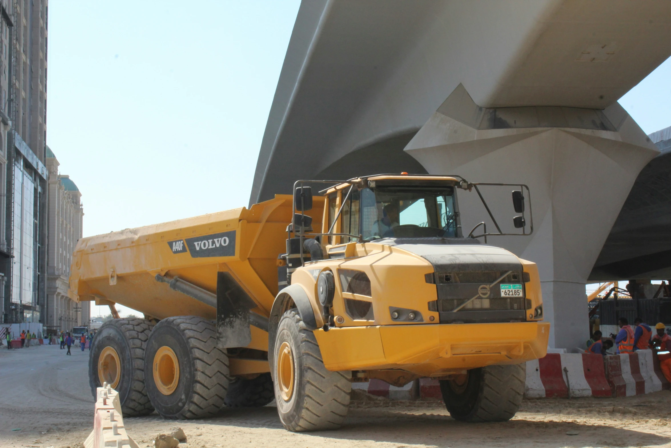 a dump truck parked in front of a building with workers walking by