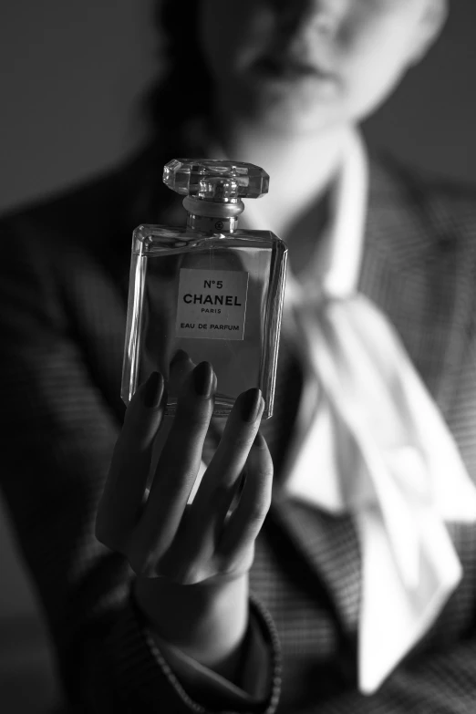 woman in business attire with jacket holding up an empty chanel bottle