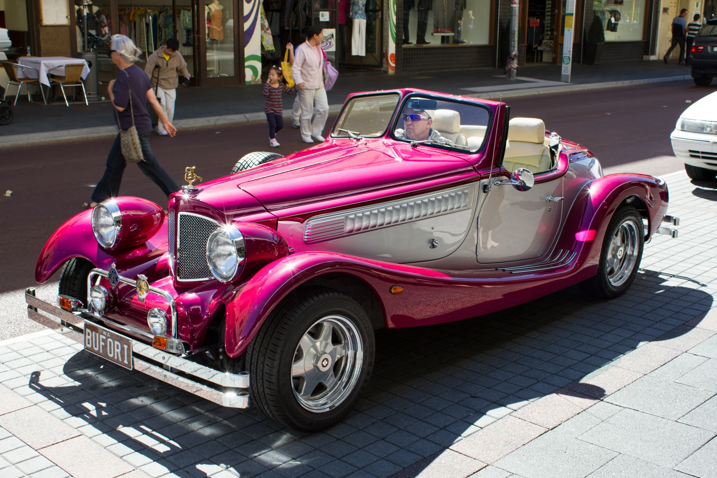 a pink vintage car on the street is parked