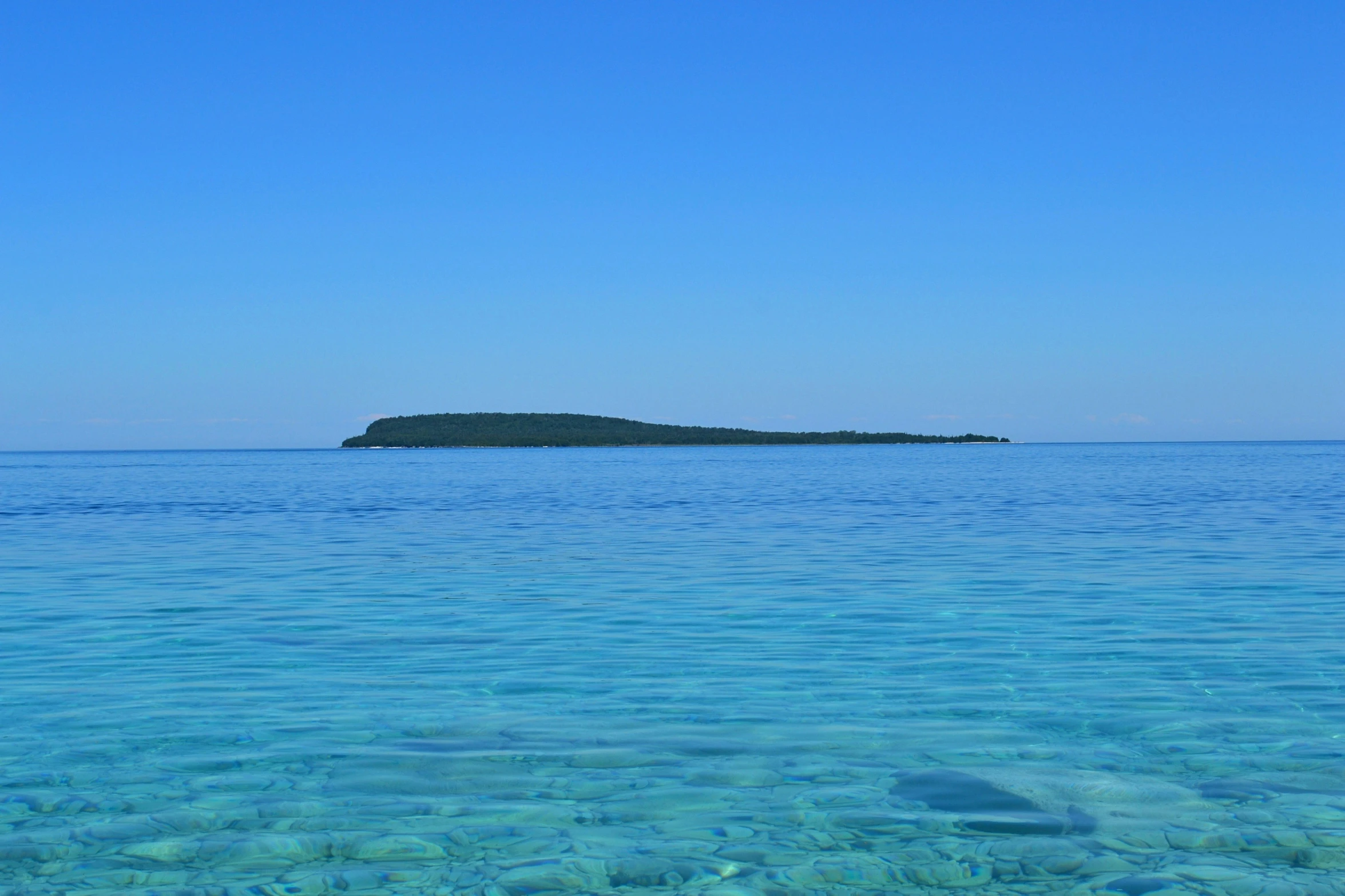 the ocean with blue water and small island in the background