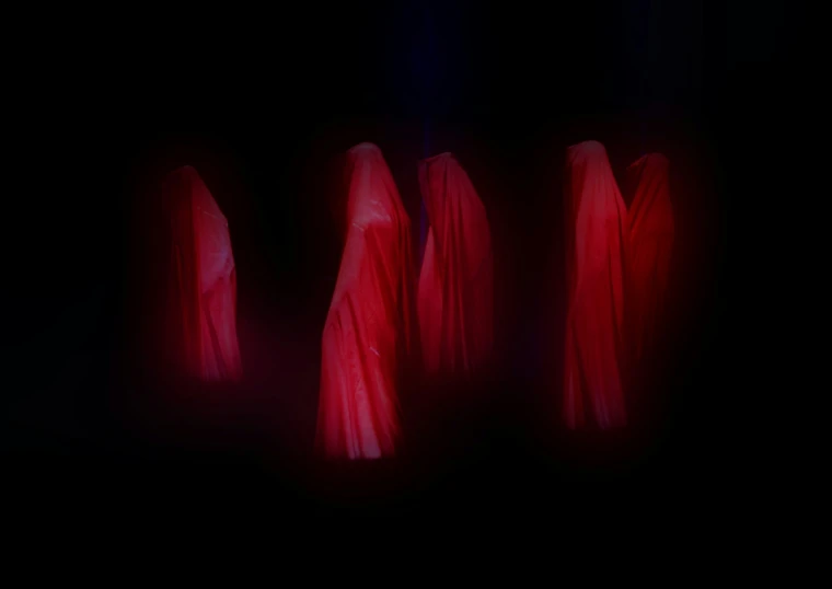 four red clothed garment stands in a dark area