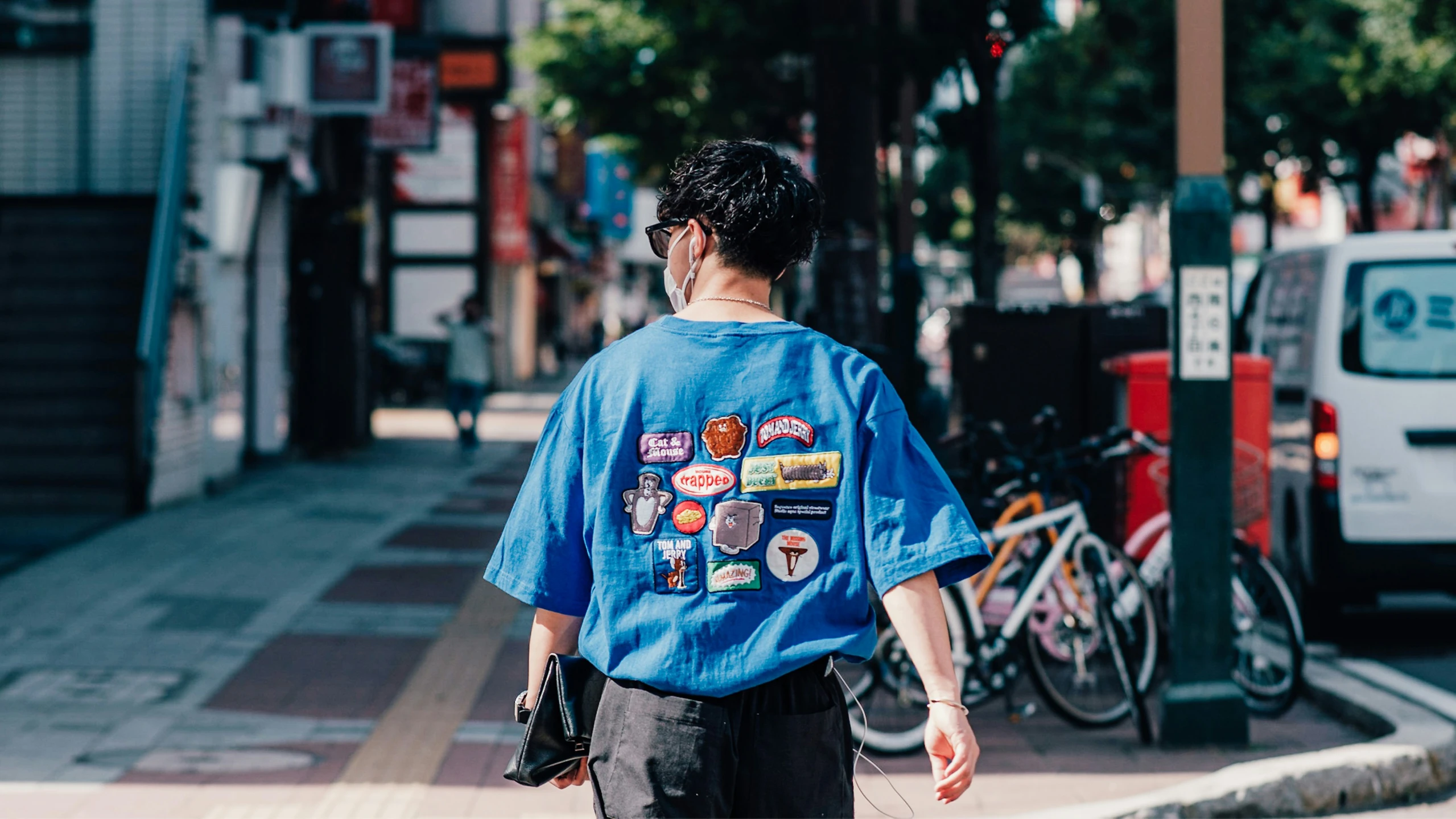 the person is walking down the sidewalk in a blue shirt