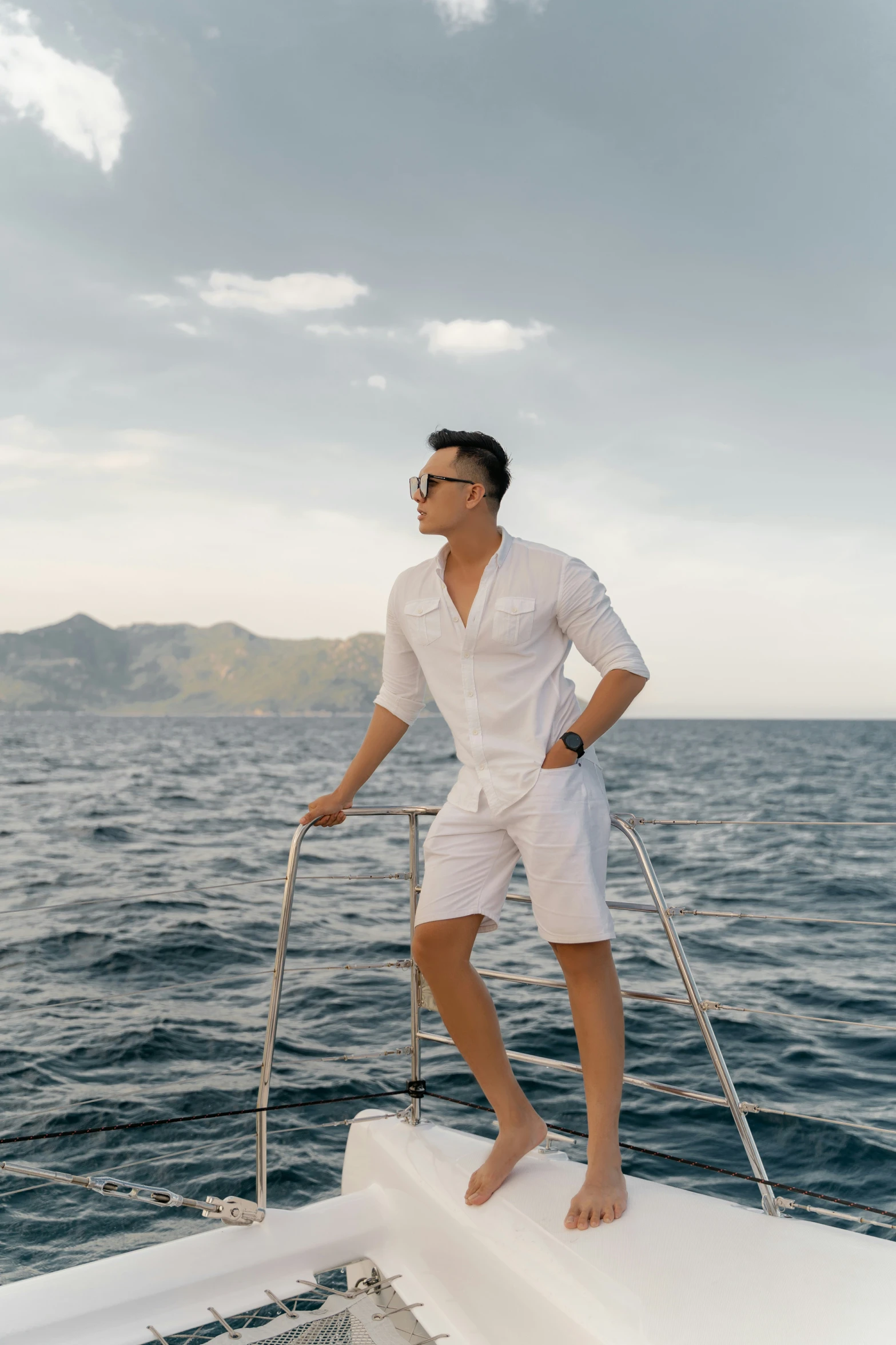 man in white shirt and sunglasses posing on the top of a boat