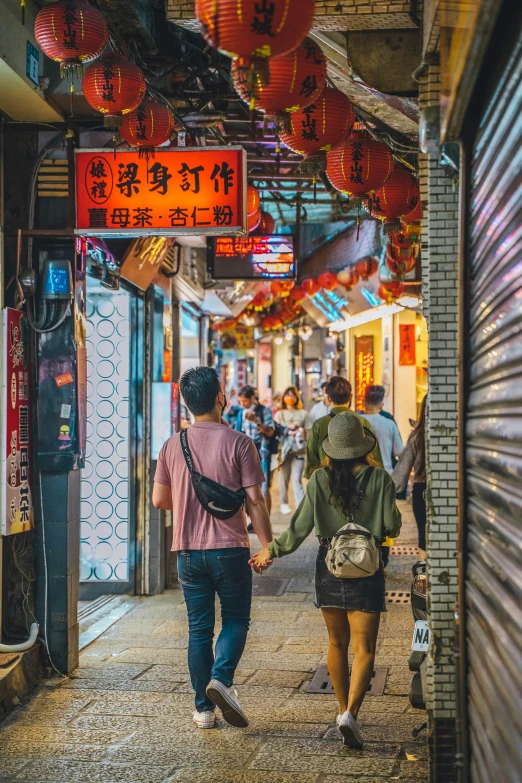 a man and woman walk hand in hand through an asian market