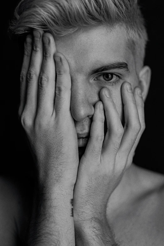 a man with blond hair has his hand on his face