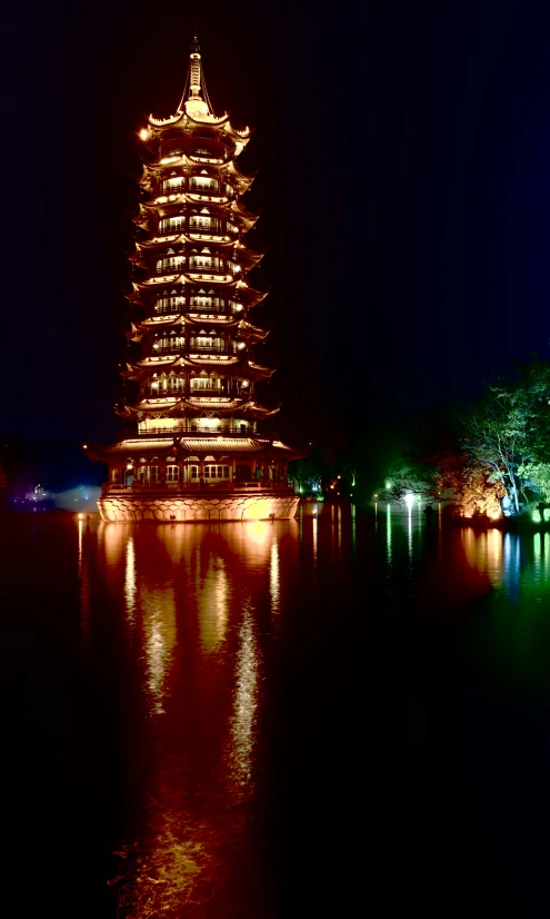 a very tall tower sitting above a lake filled with lights