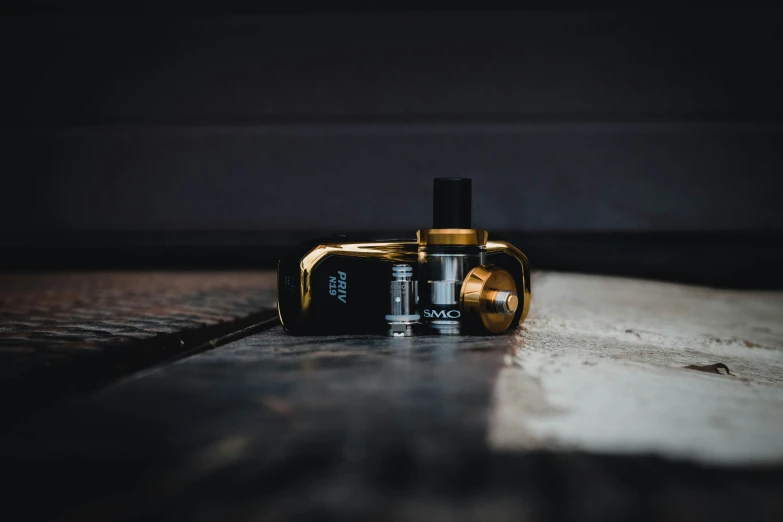 a yellow vapor bottle with a black top and no cap sitting on a table