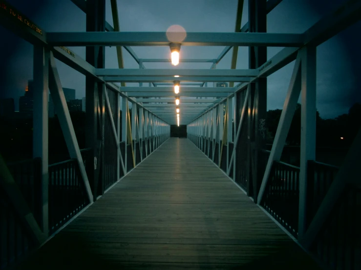there is a wooden bridge at night with lights on