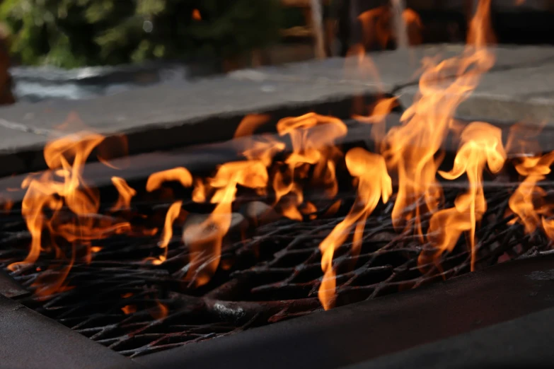 fire on top of a grill near a brick wall