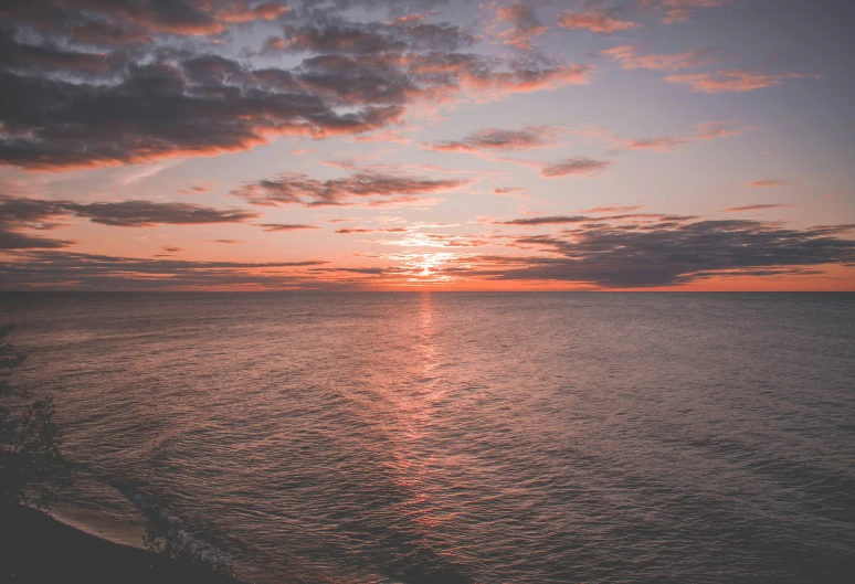 a sunset over the ocean with clouds and water