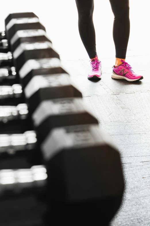 a women's pink shoe standing next to a row of black and white benches