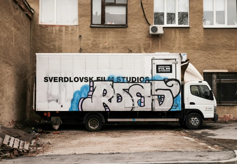 the truck is parked next to an old building with graffiti
