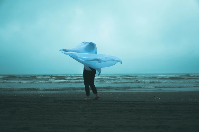 a person standing on top of a beach holding a surfboard