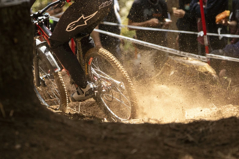 a downhill biker rides through muddy terrain as others watch