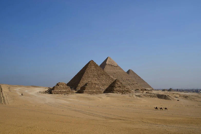 large pyramids in the desert and two men walking towards it