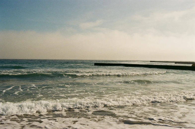 a sea view with waves and pier on the shore