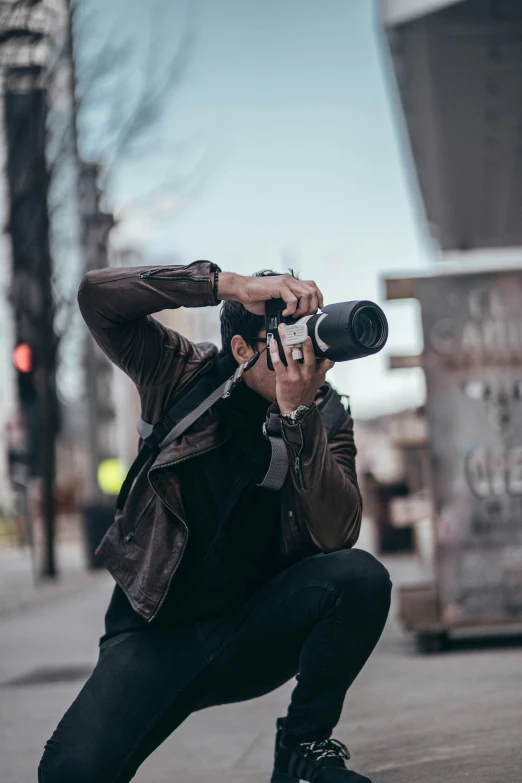 a man holding up a camera while wearing a jacket