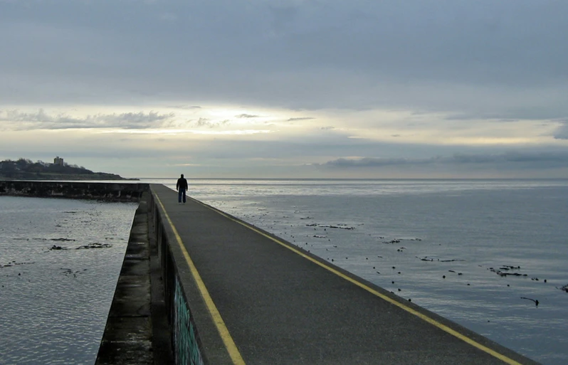 people walking on a pier at the edge of a body of water