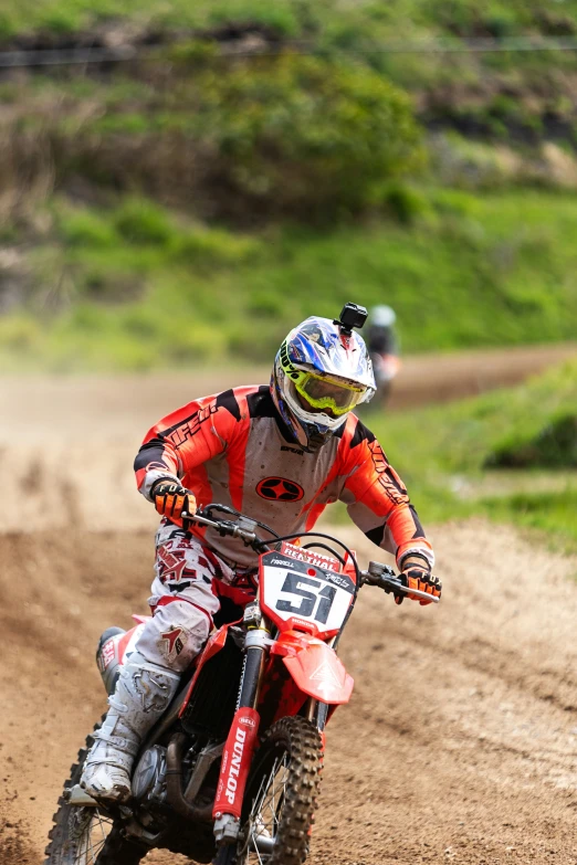 a man riding on the back of a motorcycle on a dirt road