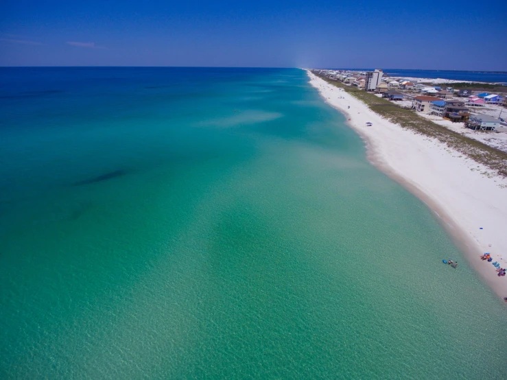 an aerial view of beach with white sand and clear blue ocean