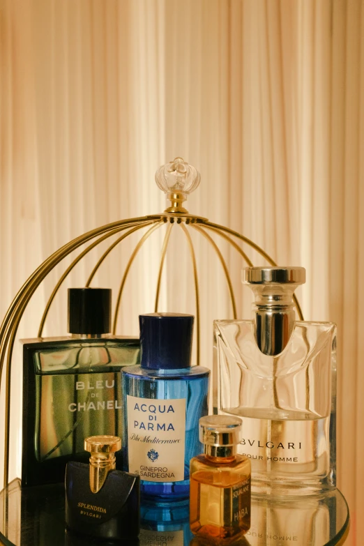 three perfume bottles in a metal cage on a table