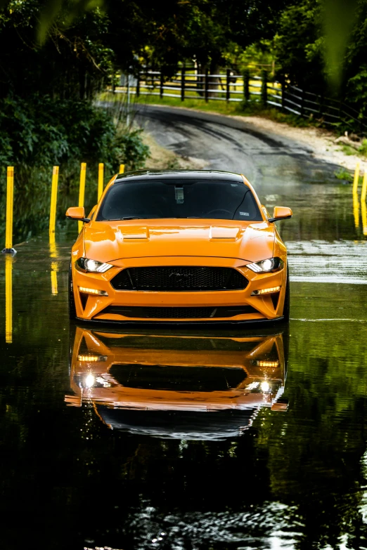 a bright yellow mustang car on the wet road