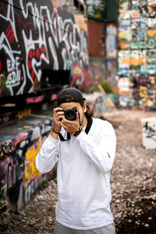 a young man taking a picture in front of graffiti wall