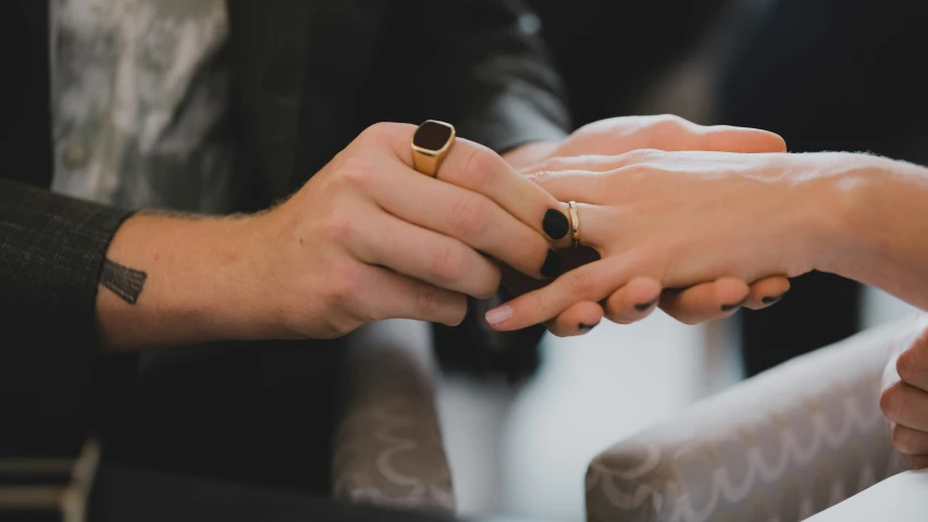 two people holding hands and holding wedding rings