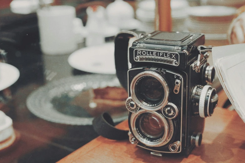 an old camera sitting on a table near dishes