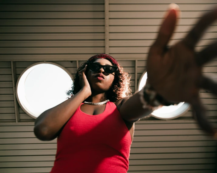 an african american woman in sunglasses making a victory sign