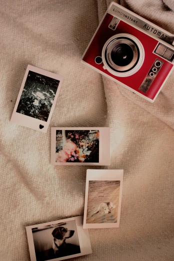 the polaroid camera is on a bed covered with pos