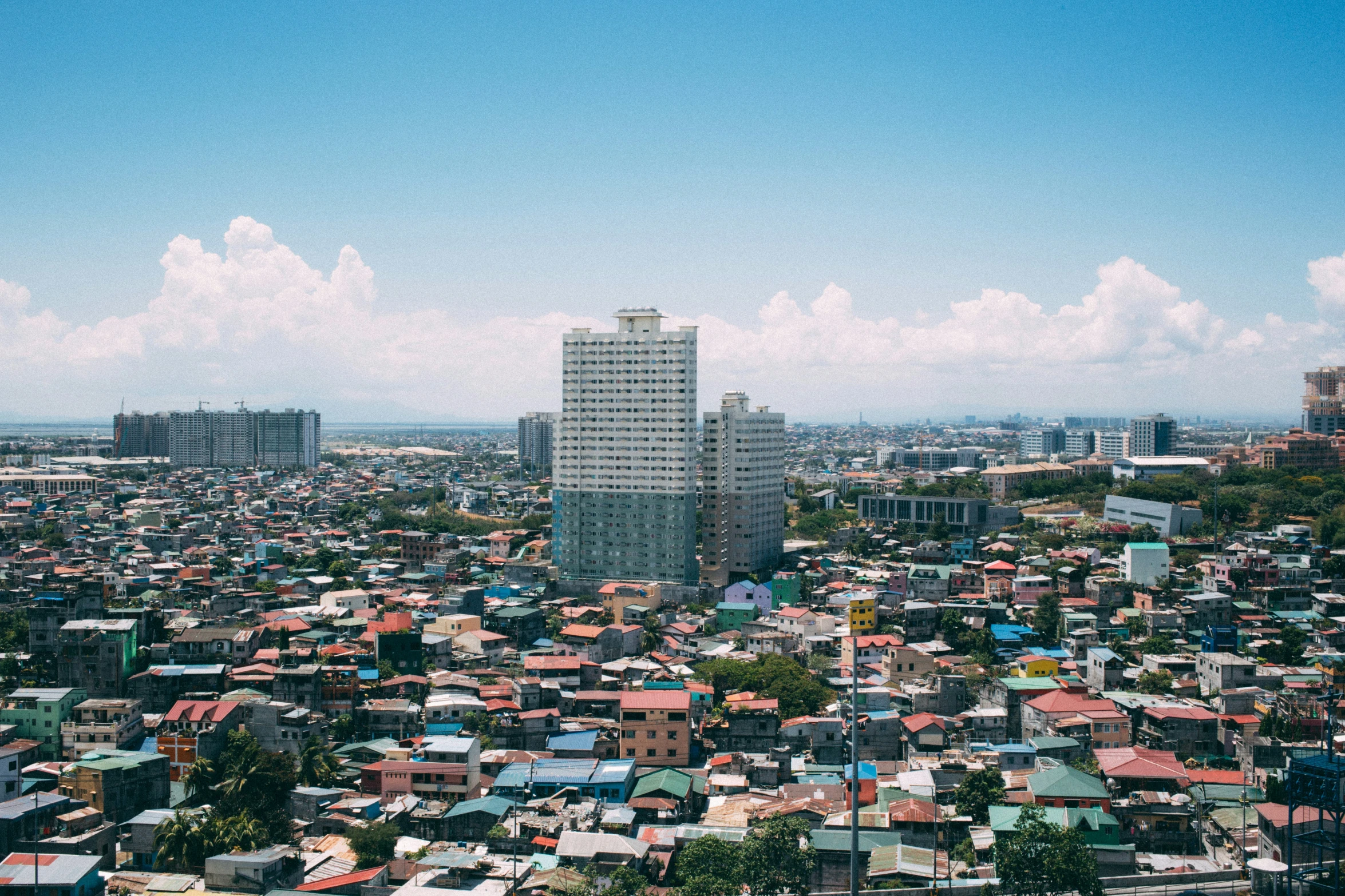 a large city with tall buildings is surrounded by mountains and clouds