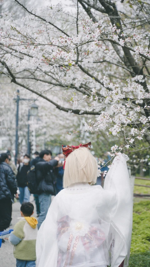 an older woman dressed in a blanket is walking by the trees