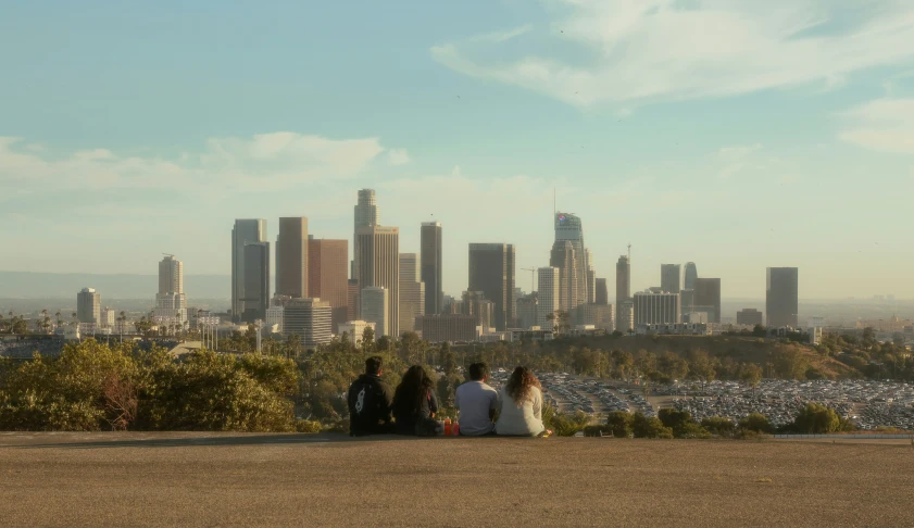 people sitting on top of a large hill overlooking a city