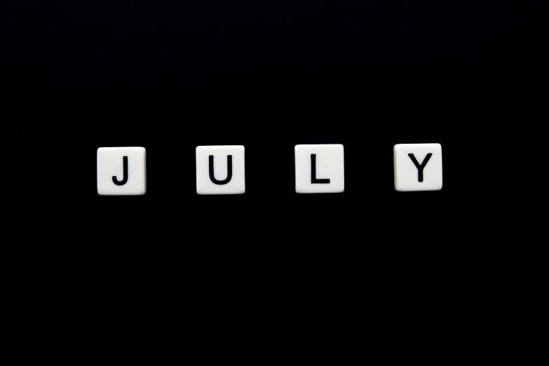 the word july spelled with white scrabble letters