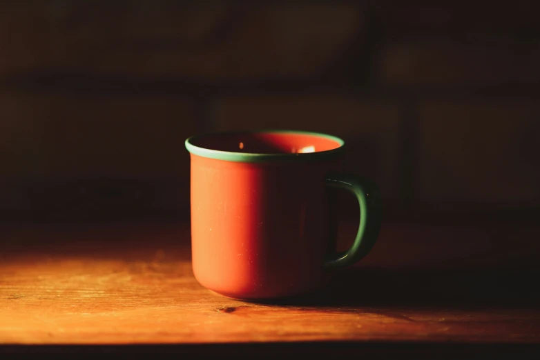 an orange coffee cup is sitting on a table