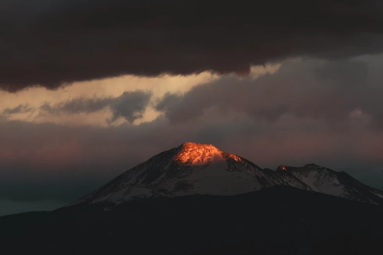 the sun shining through the clouds near a mountain