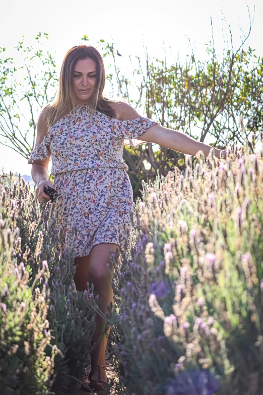 a girl in a flowery dress walking through a field