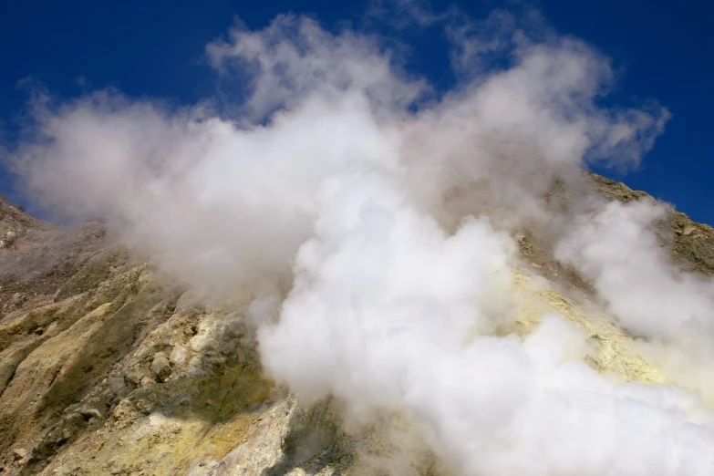 there are several clouds flying through the sky near a mountain