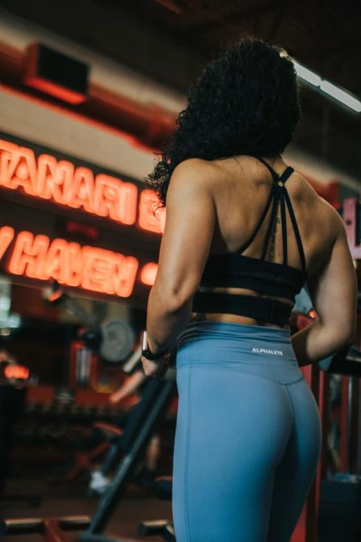 a woman with a cross - back top and blue pants is at the gym