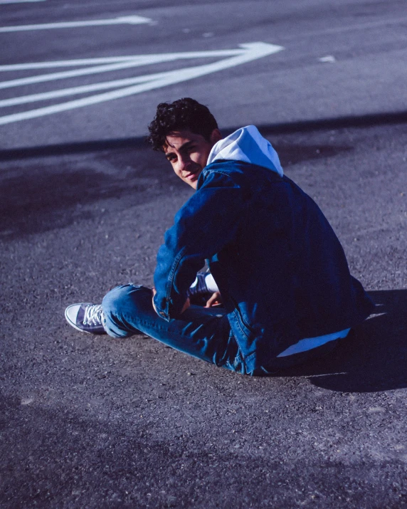 a boy is squatting down in the parking lot