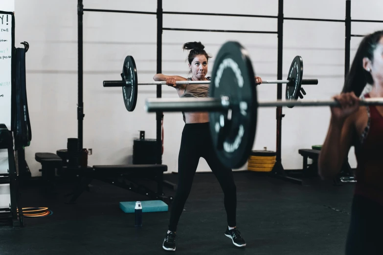 a person in a gym squats to lifting up a barbell