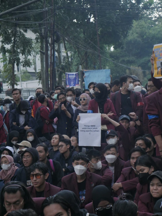 several people in a crowd wearing face masks, protesting