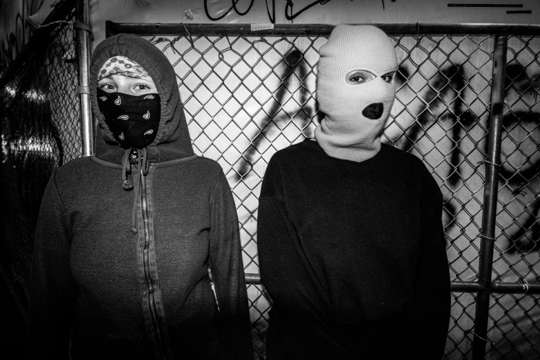 two people wearing animal masks in front of a chain link fence